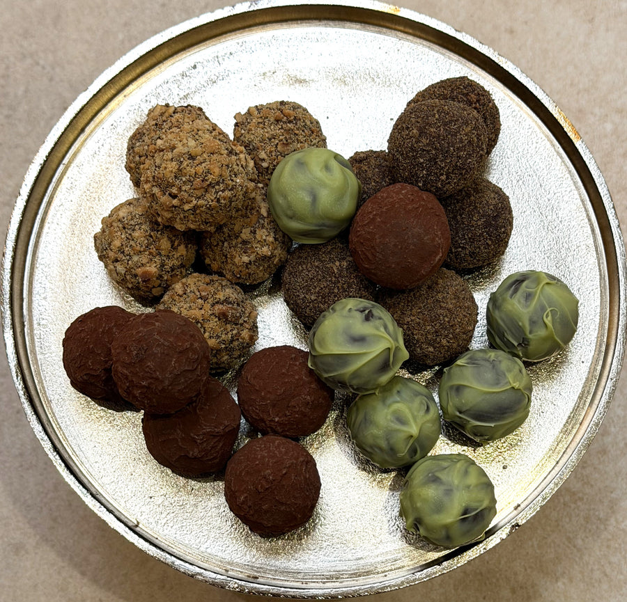 Assorted truffles including brown and green varieties on a metallic surface.