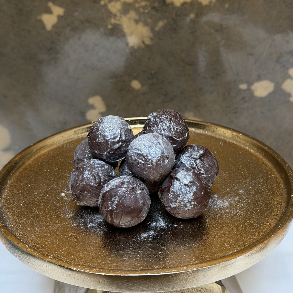 Chocolate truffles on a gold ceramic plate with a textured background