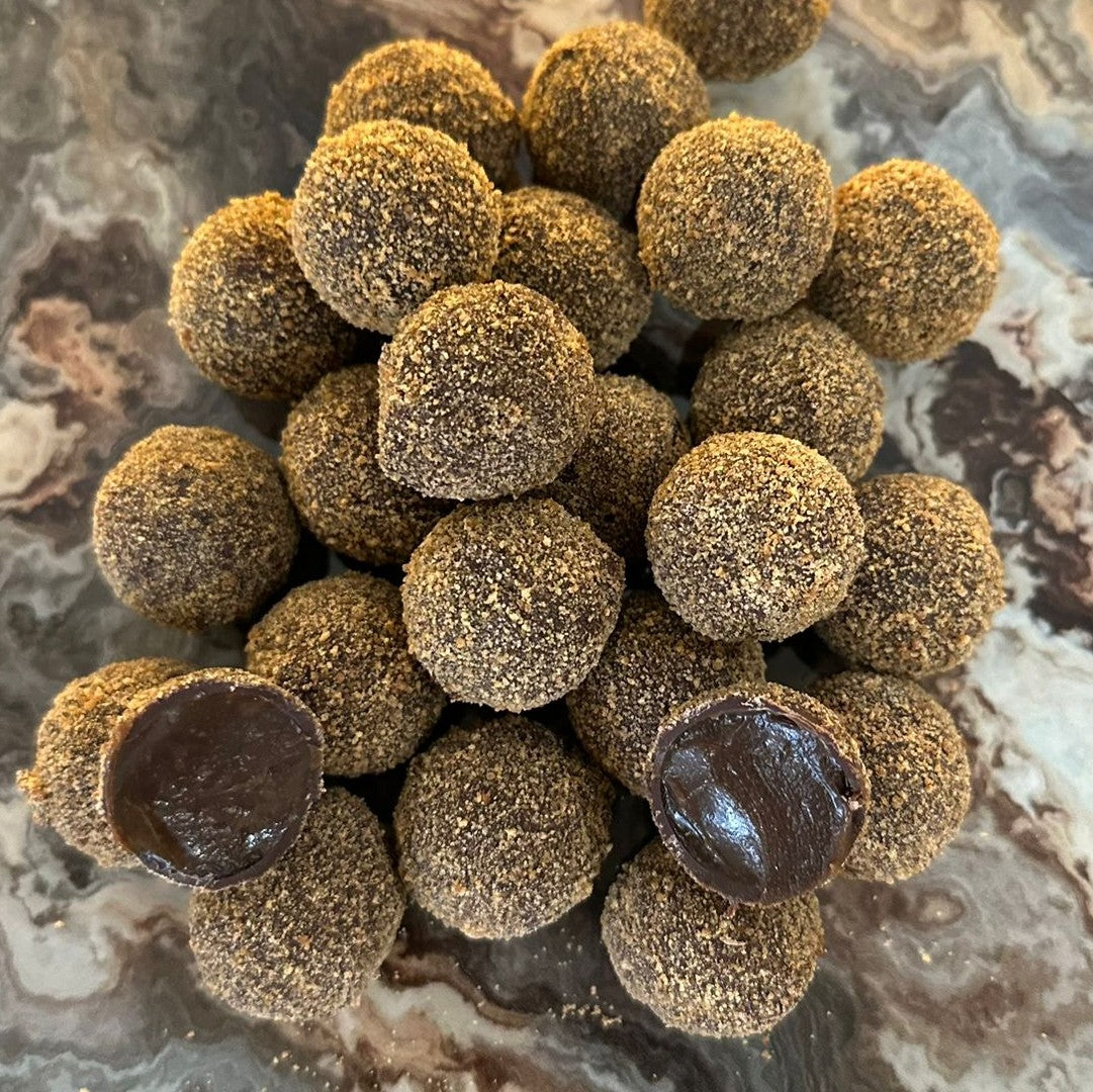 A collection of chocolate covered truffles with a caramel center, placed on a marble surface.