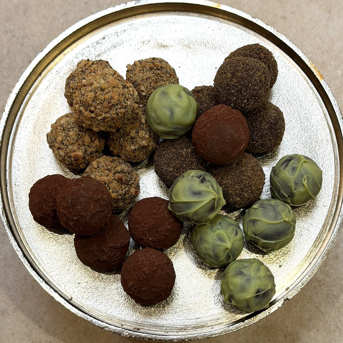 Assorted truffles including brown and green varieties on a metallic surface.