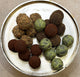 Assorted truffles including brown and green varieties on a metallic surface.